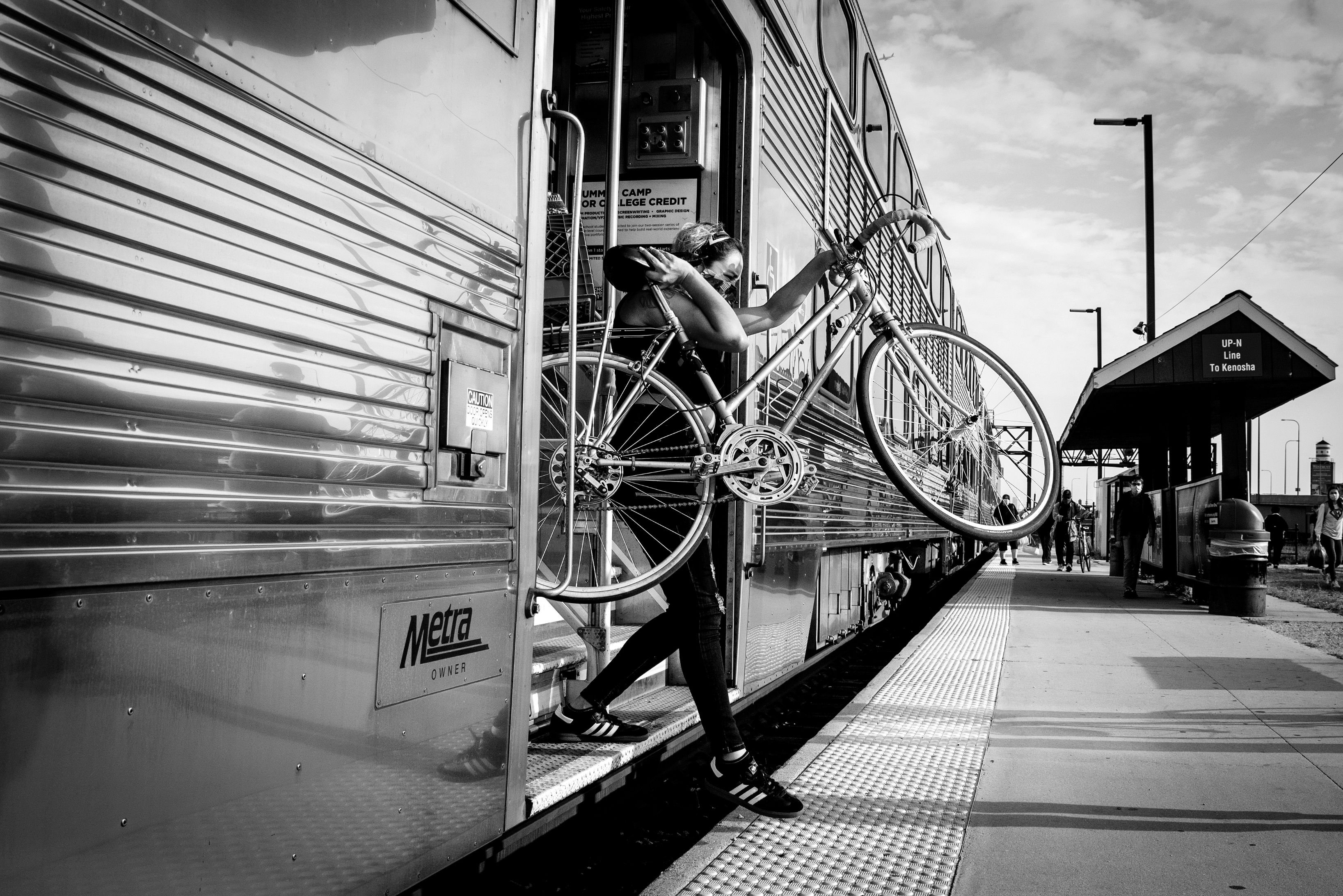 Black and white photo of a person stepping off metra stop with bike in the Bucktown neighborhood of Chicago